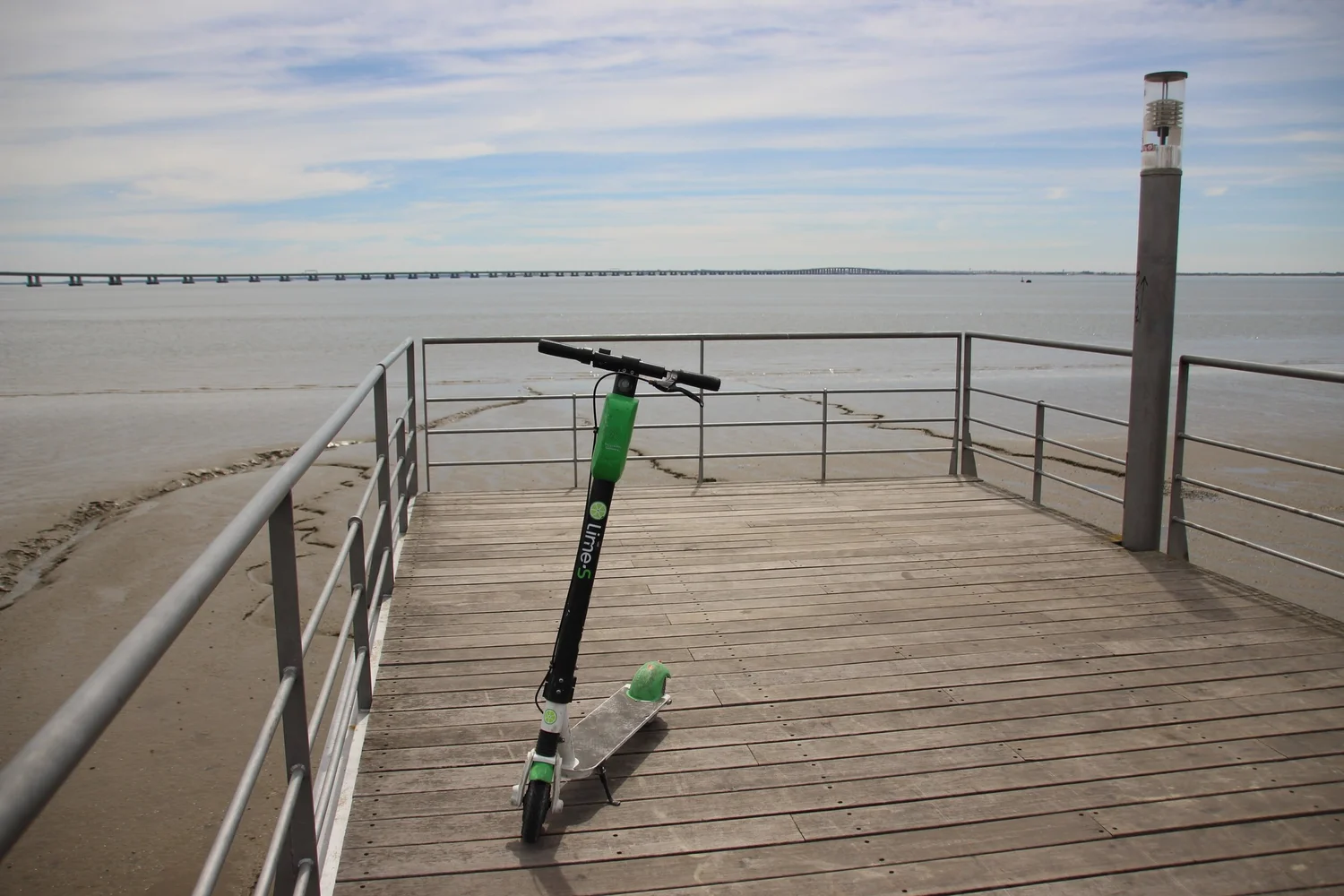 A lime e-scooter sits on a pier